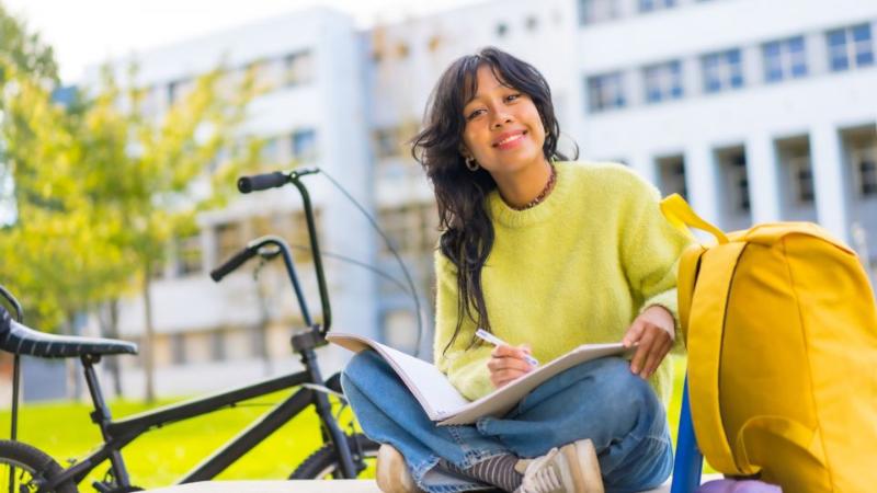 female student sitting outside reading a book